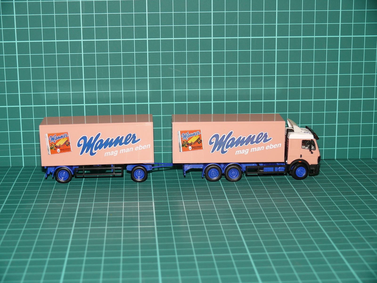 Herpa H0 – Skříňová nákladní souprava Mercedes-Benz SK 3-osý s 2-osým přívěsem „Manner mag man eben“ – H0